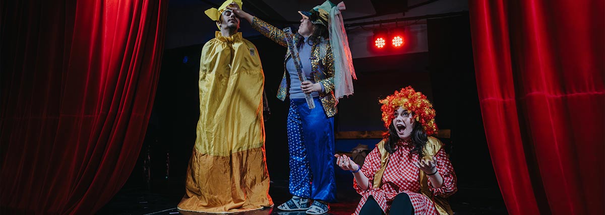 Actors dressed in colorful costumes perform an engaging theatrical scene on a decorated stage