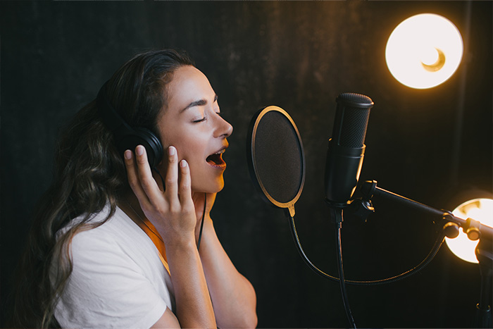 Beautiful woman singing in the studio with headphones on feat