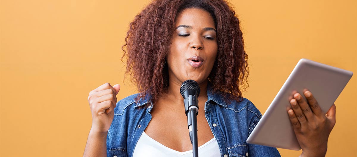 Black woman practising singing holding an ipad