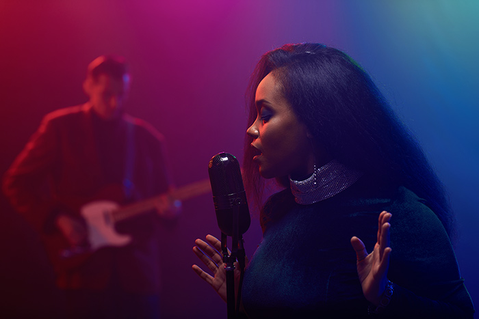Female jazz singer performing with guitarist in the background