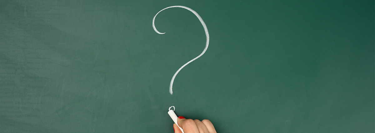 Hand writing question mark on green board
