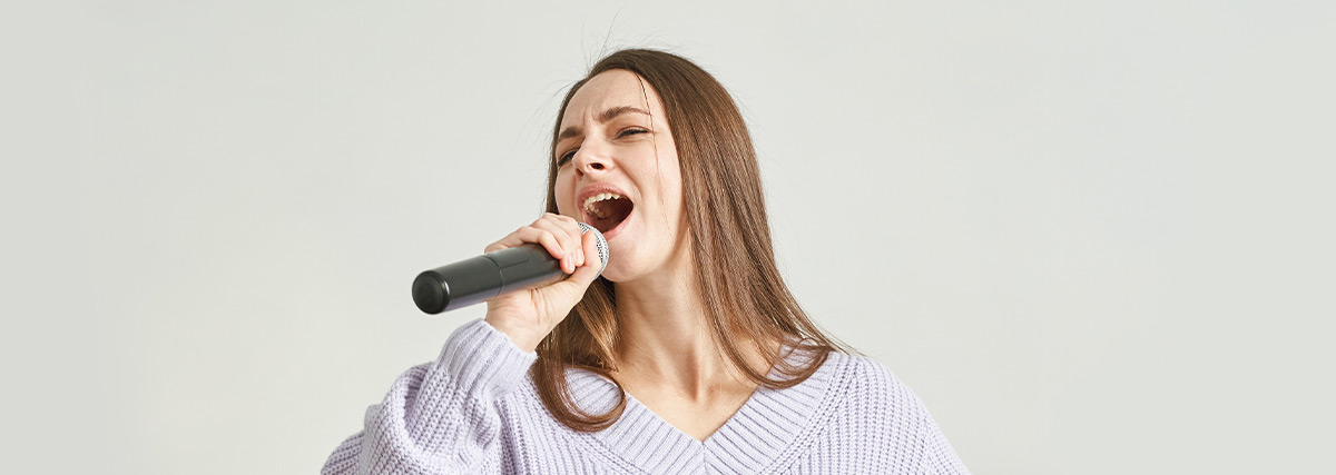 Lady with sweater singing with microphone