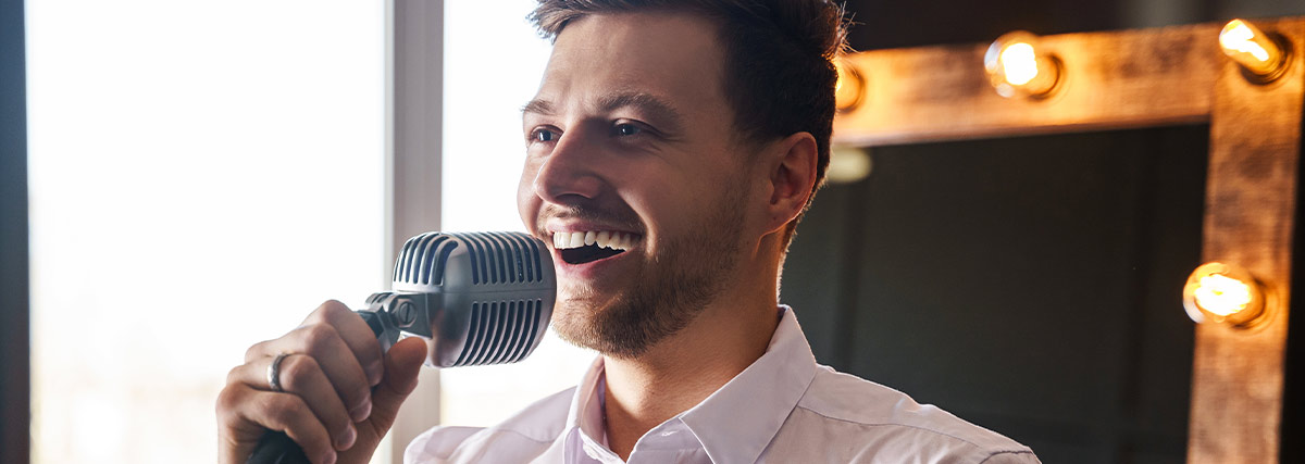 Man in white shirt smiling and singing