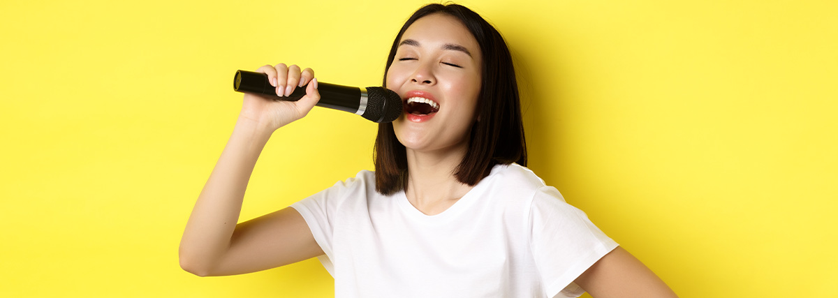 Singer practising with microphone against yellow background for vocal confidence and expression
