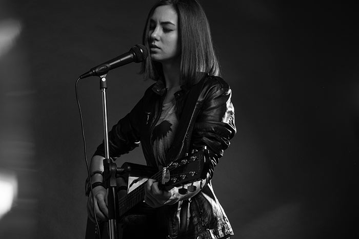 singer with guitar on stage feat