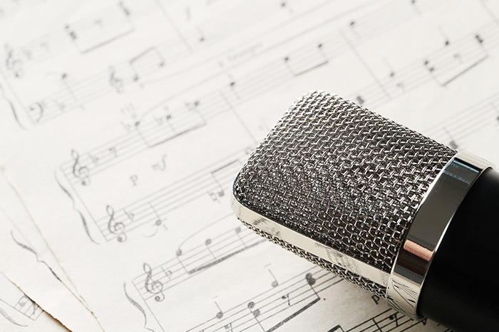 Studio microphone on sheet music for learning singing and octaves