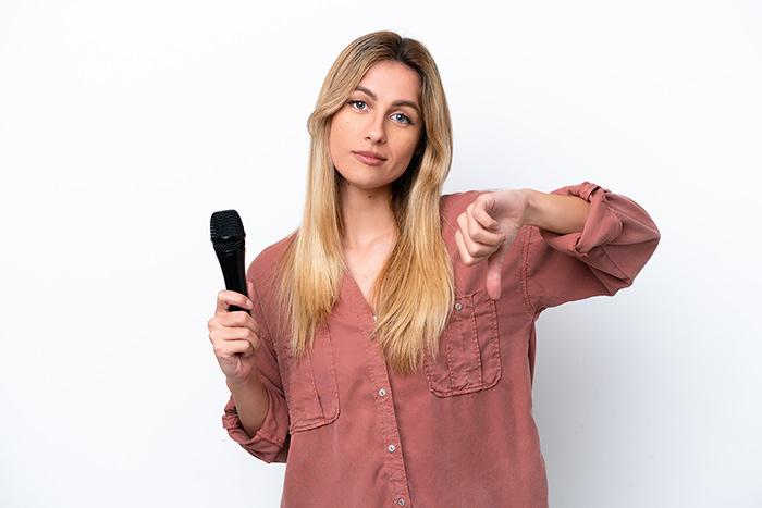 Woman holding a microphone and with other hand showing thumbs up