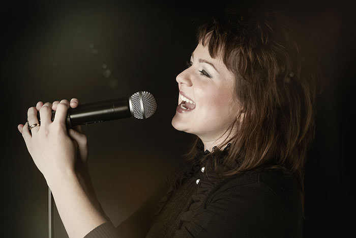 woman holding microphone singing feat