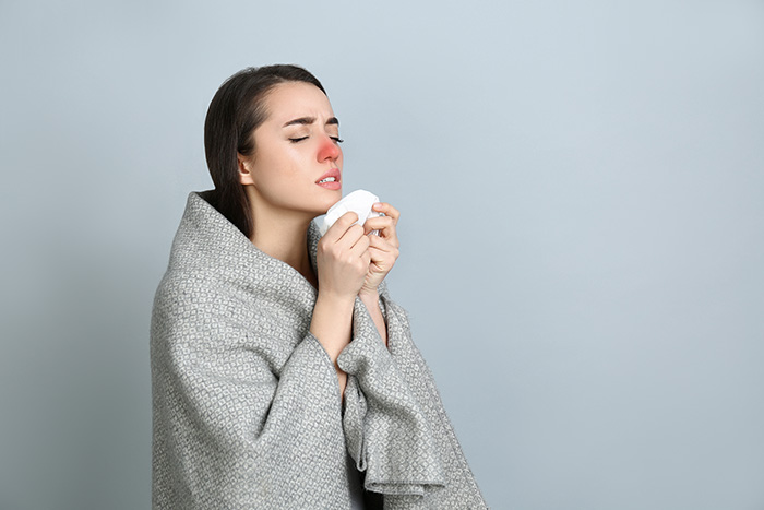 Woman with blanket sneezing feat