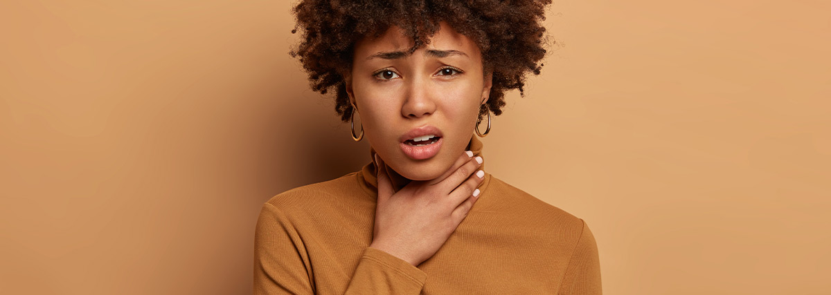 Woman with brown blouse touching her throat