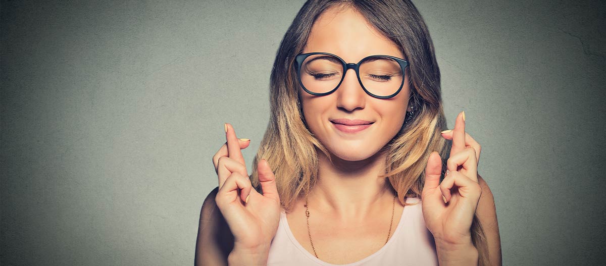 Woman with eyes closed and crossed fingers