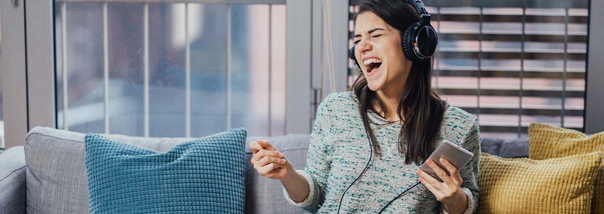 Woman with headphones on singing at home
