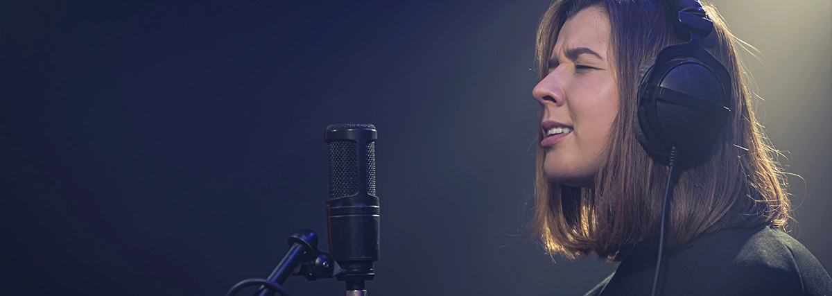 Woman with headphones on singing passionately