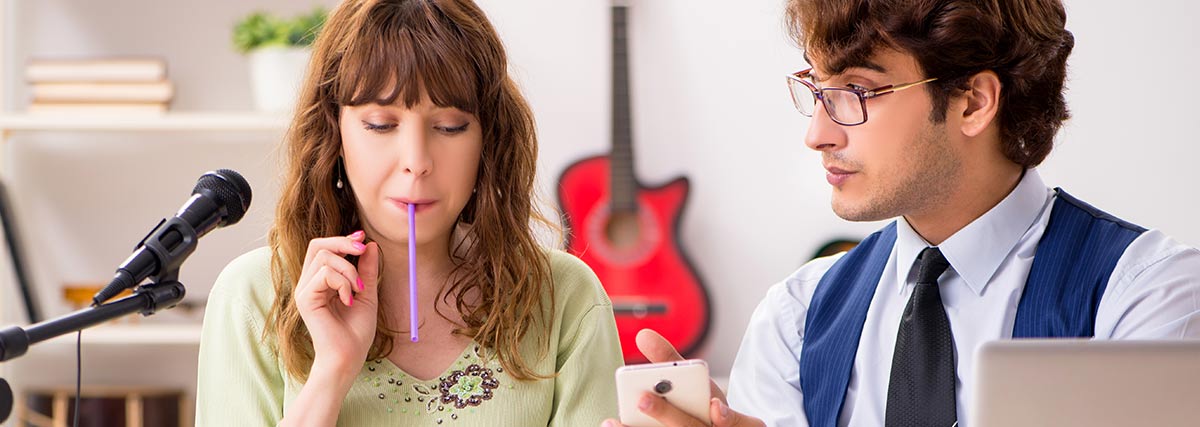 Woman with straw in her mouth along with her vocal teacher