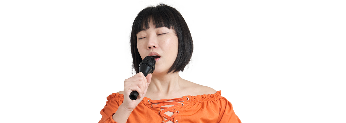 Lady in orange blouse singing with eyes close